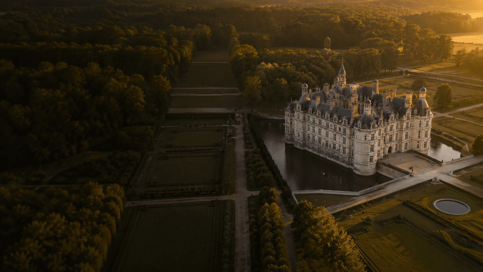 Vue aérienne d'un grand domaine et de ses jardins à la française au coucher du soleil